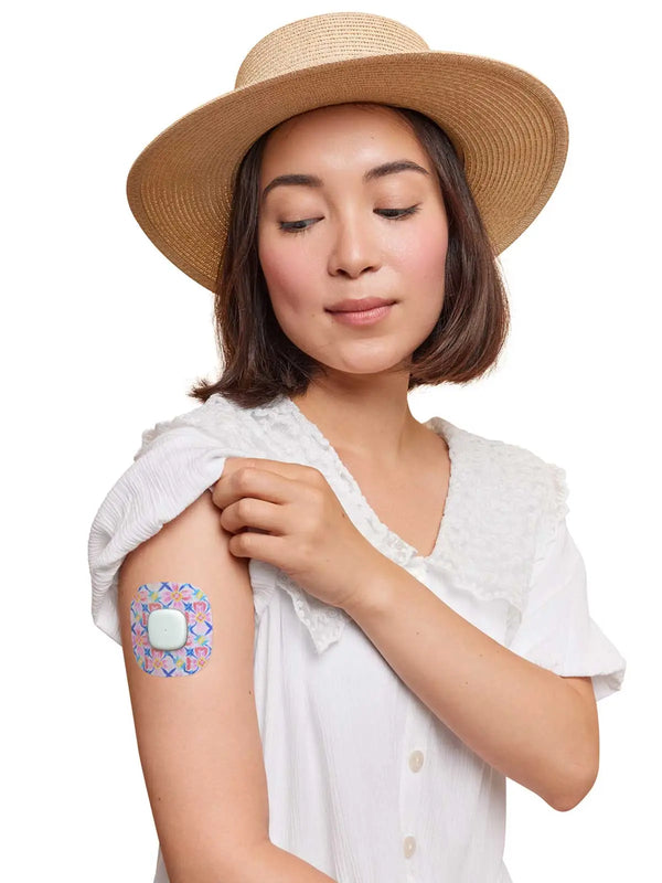 Woman wearing a Simplera Sensor Patch on her arm, showing colorful design and secure fit.