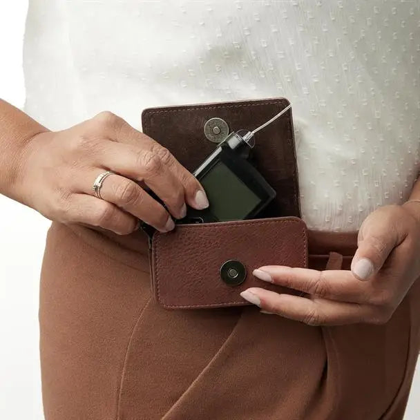 Brown leather insulin pump cases, a protective and stylish accessory for daily use, shown worn on a person's waist. Obraz