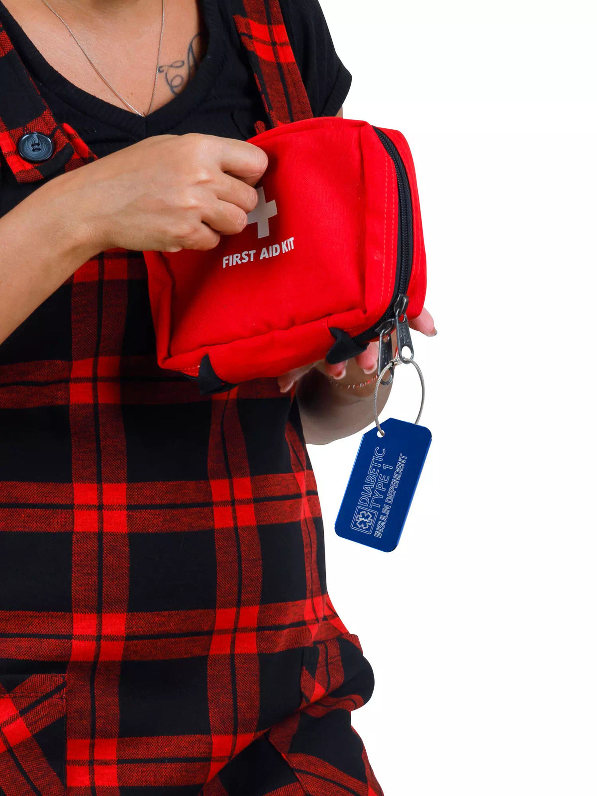 Person holding a red first aid kit with a blue 'Diabetic Type 1 Insulin Dependent' luggage tag attached.