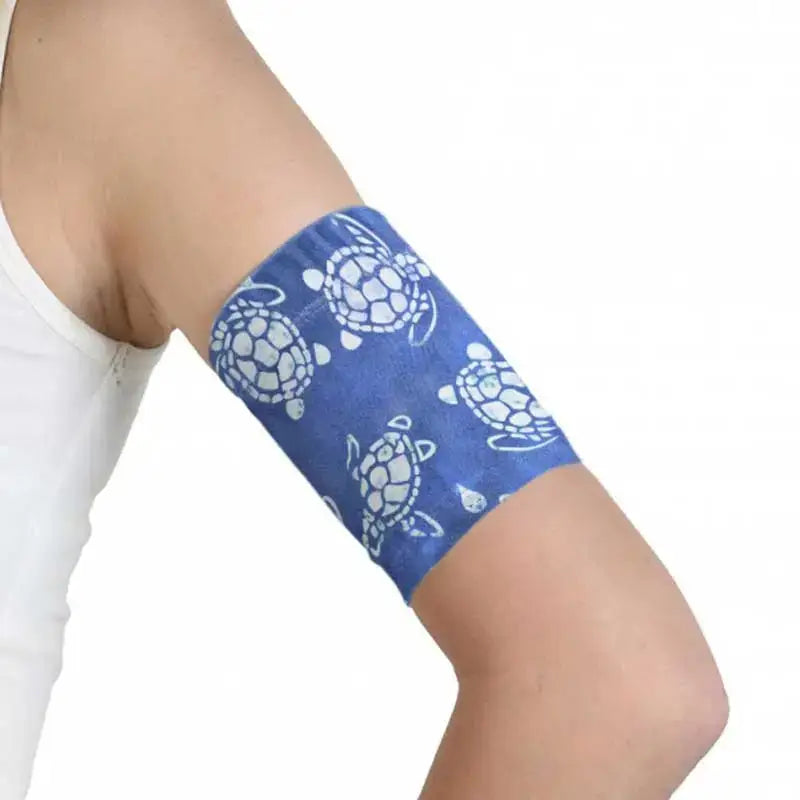 Glucose sensor armband for kids with turtle print, securely fitted on arm.